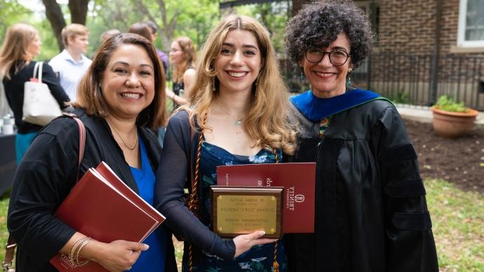 An honor award recipient poses for a photo with a fcaulty member and family member while holding her award