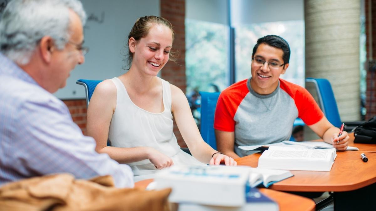 Professor and two students sitting at table talking