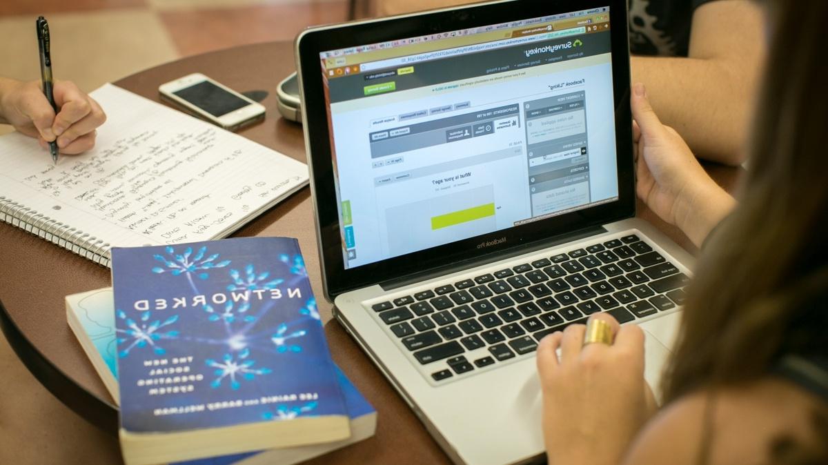 Student at a laptop with a couple literature books on the table