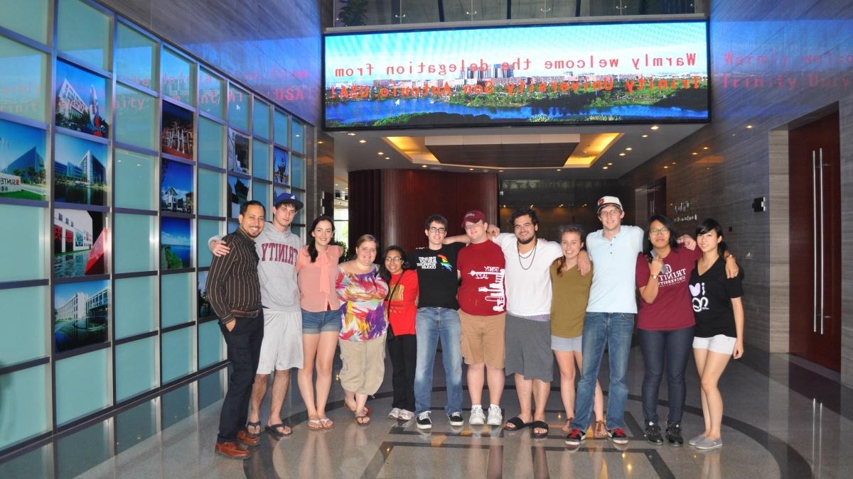 Group of faculty and students posing under sing that says "welcome delegation fro 圣澳门金沙赌城线上游戏"