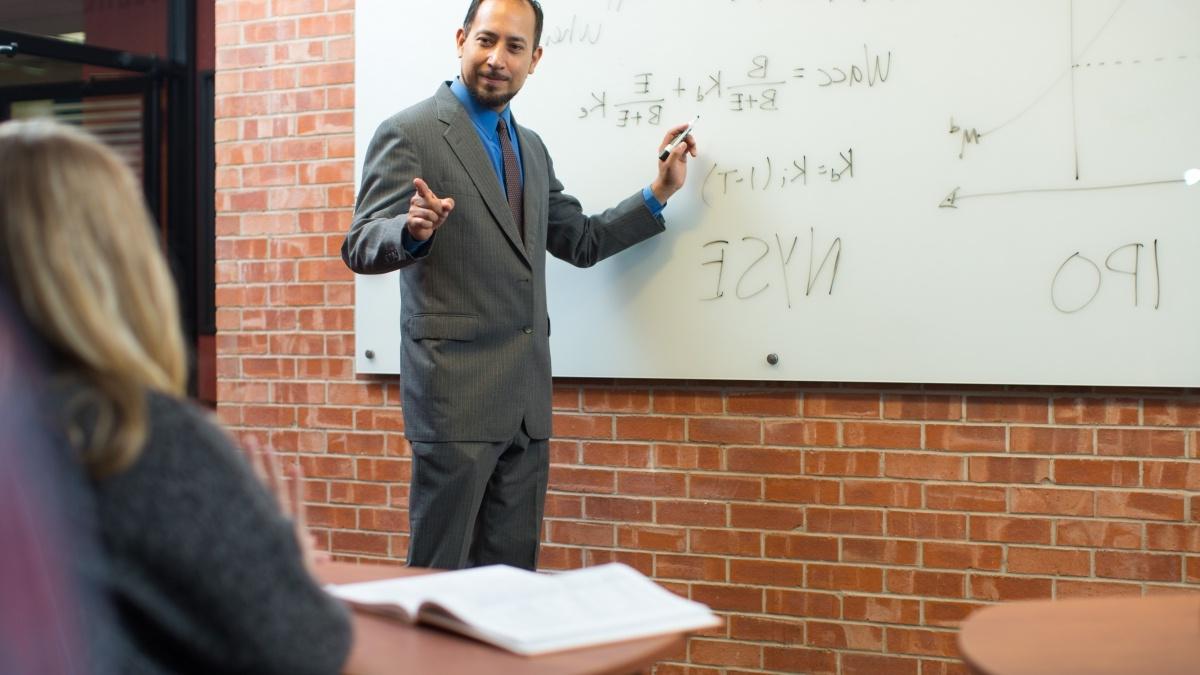 Professor at the whiteboard presenting to class.