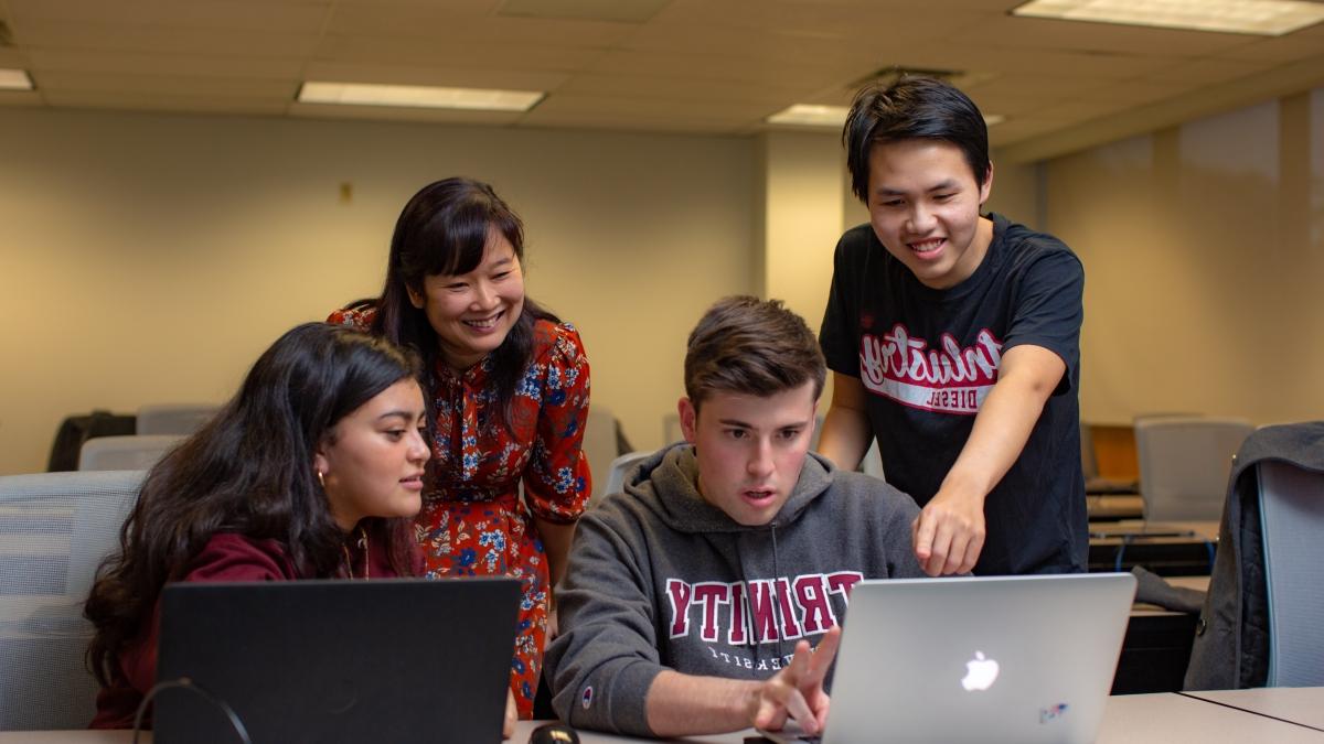 Student points to a computer screen while working with a group